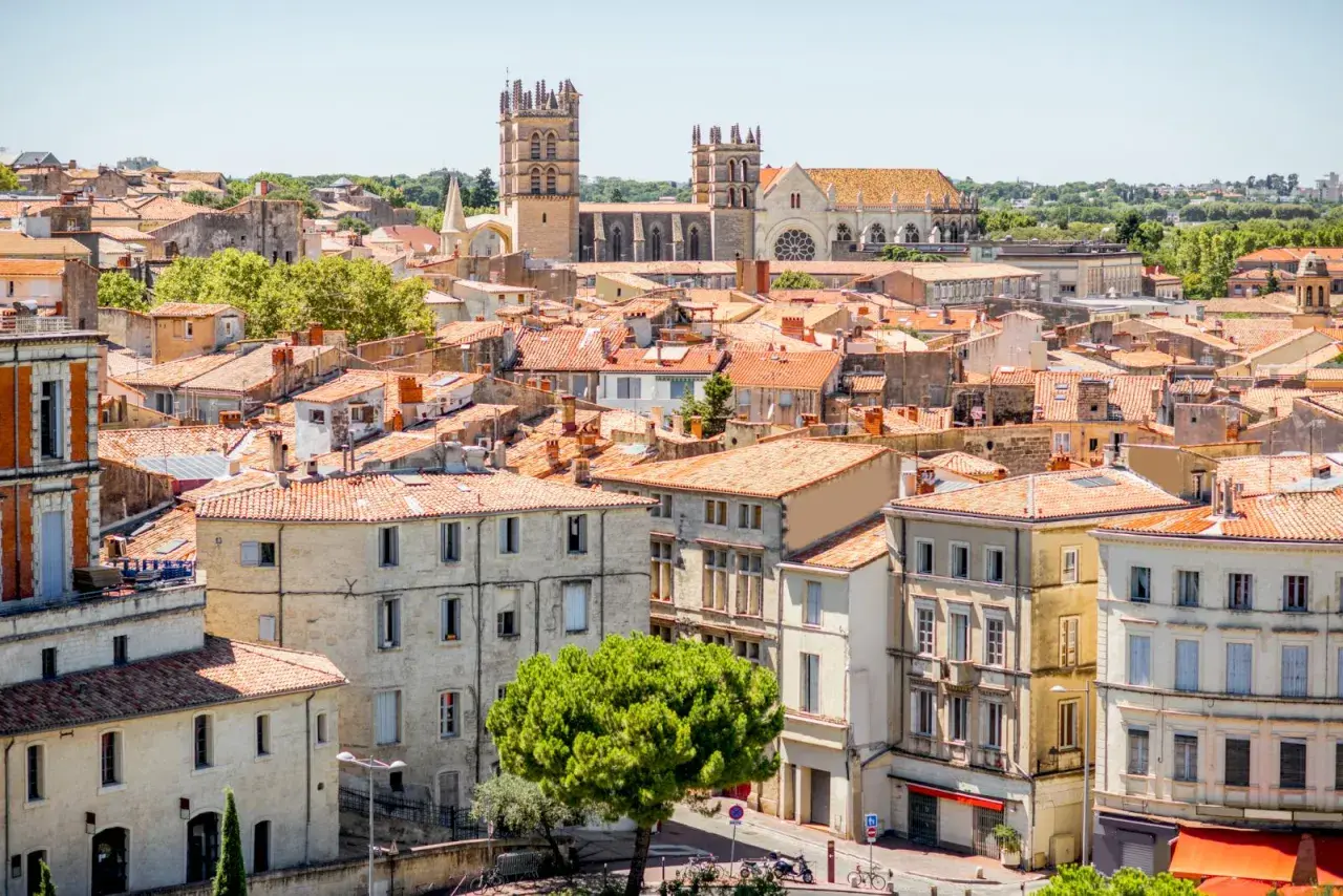 En vy över mysiga byar i Languedoc med sina terrakottafärgade tak och en imponerande katedral i bakgrunden.