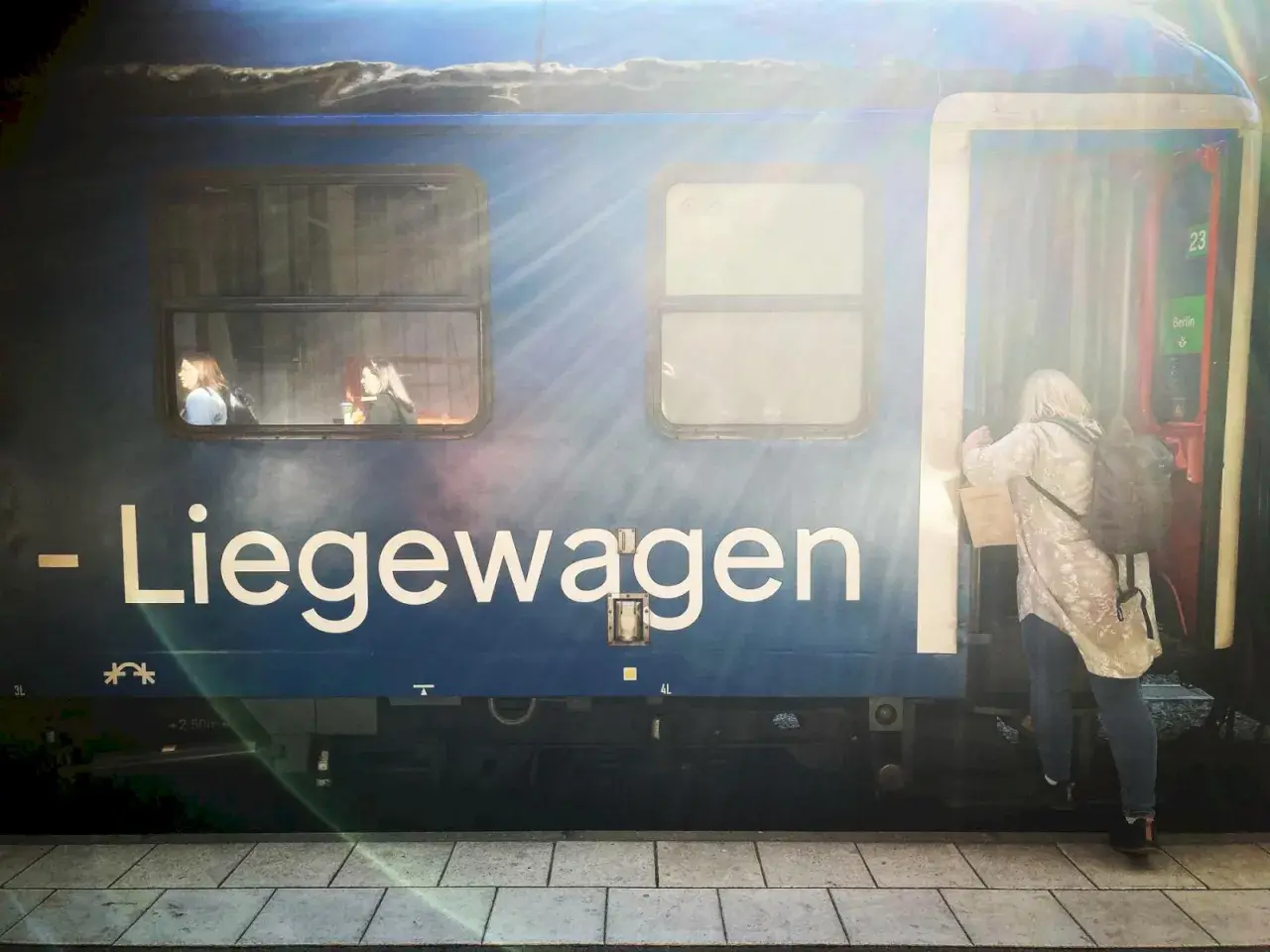 En kvinna kliver på ett tåg med destination Berlin. Två passagerare tittar ut genom fönstret.