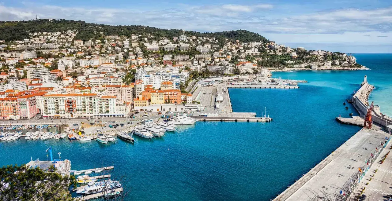 Hamnen i Nice med sina färgglada hus och gröna kullar. En perfekt startpunkt för en resa, kanske till Paris?
