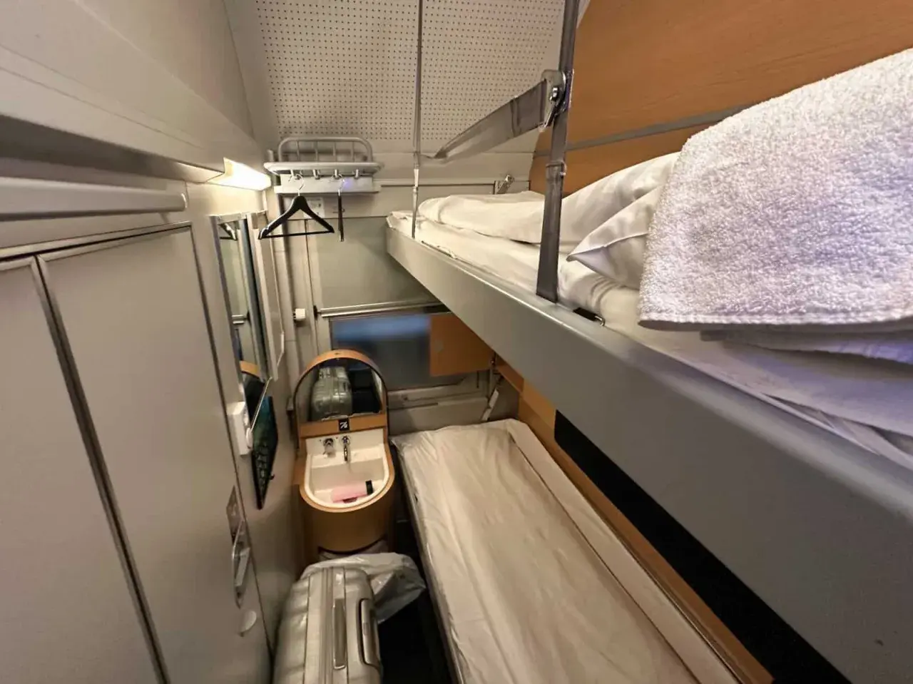 Sovhytt på ett nattåg Stockholm med våningssängar, handfat och bagage.