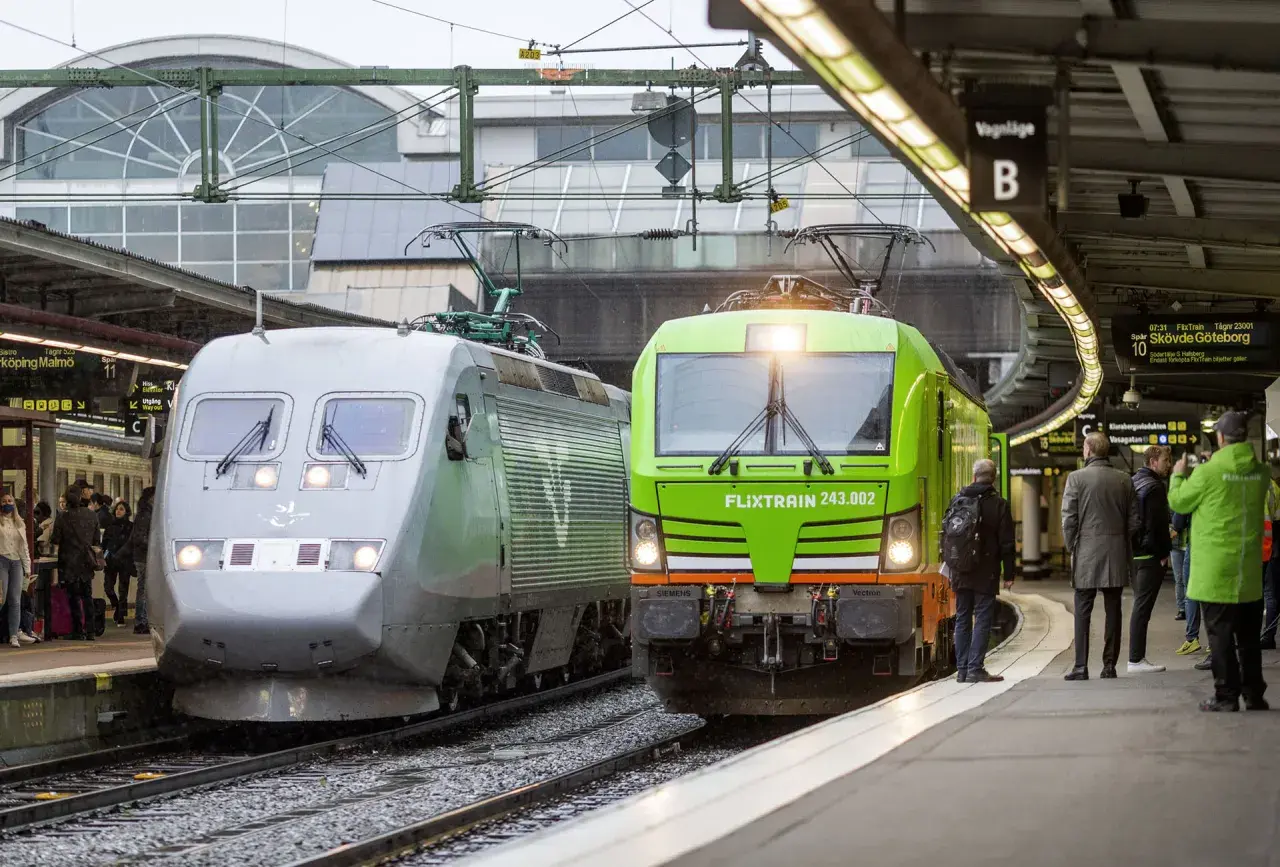 Två tåg, ett silverfärgat och ett grönt FlixTrain, står vid perrongen. En perfekt start för en paketresa tåg Sverige.