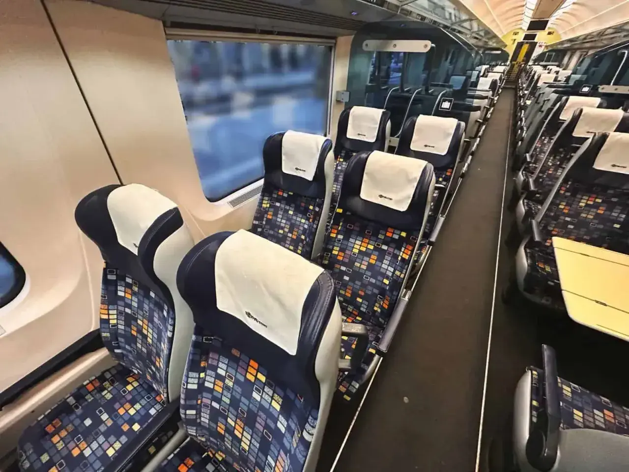 Tomma säten i en nattåg till München. Mörka säten med färgglatt mönster och vita nackstöd.