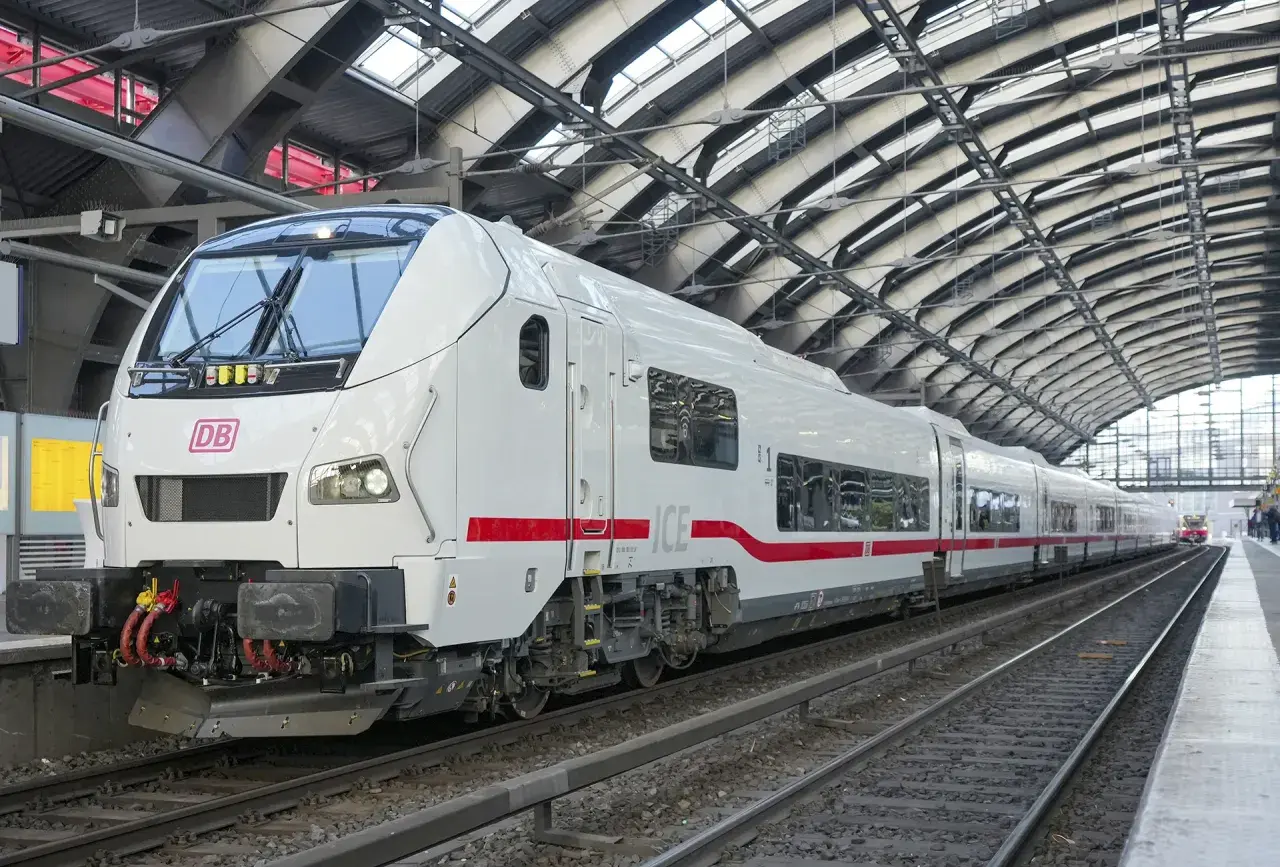 Ett modernt vitt ICE-tåg med röda detaljer står på en station i Hamburg. Tåget är redo att ta passagerare på en resa.