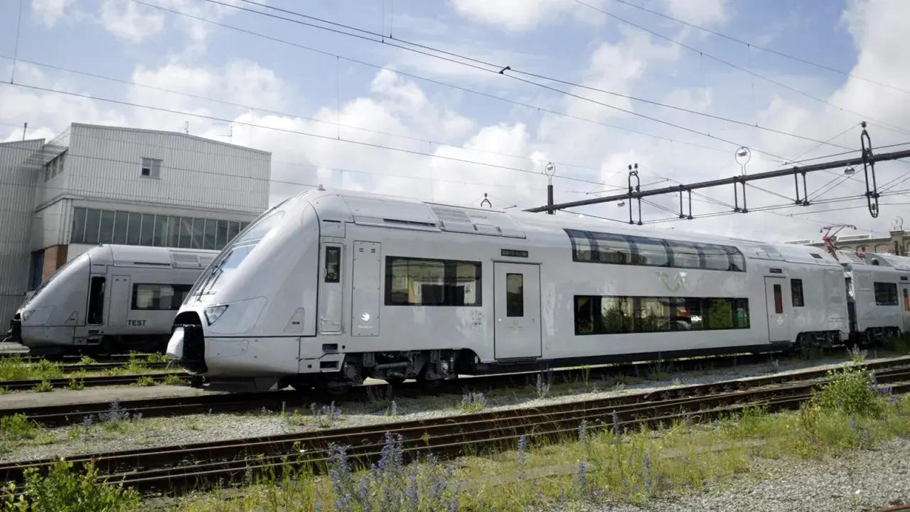 Två moderna SJ-tåg står uppställda på spåret. Ett av tågen har texten "TEST" på sidan, redo för äventyr med ett sj tågluffarkort.