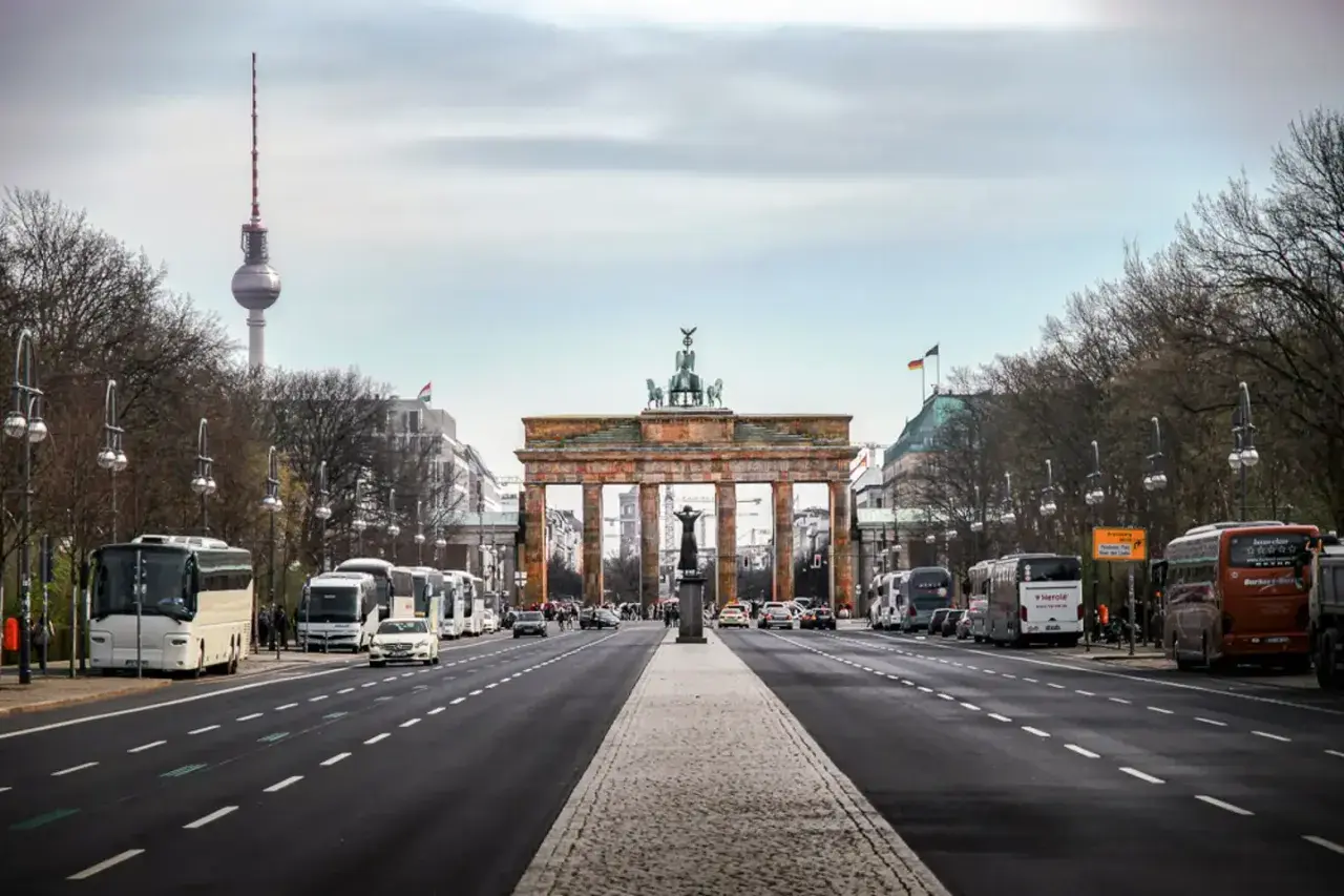 Brandenburger Tor och TV-tornet syns tydligt under en resa till Berlin. Bussar och bilar trafikerar gatan.