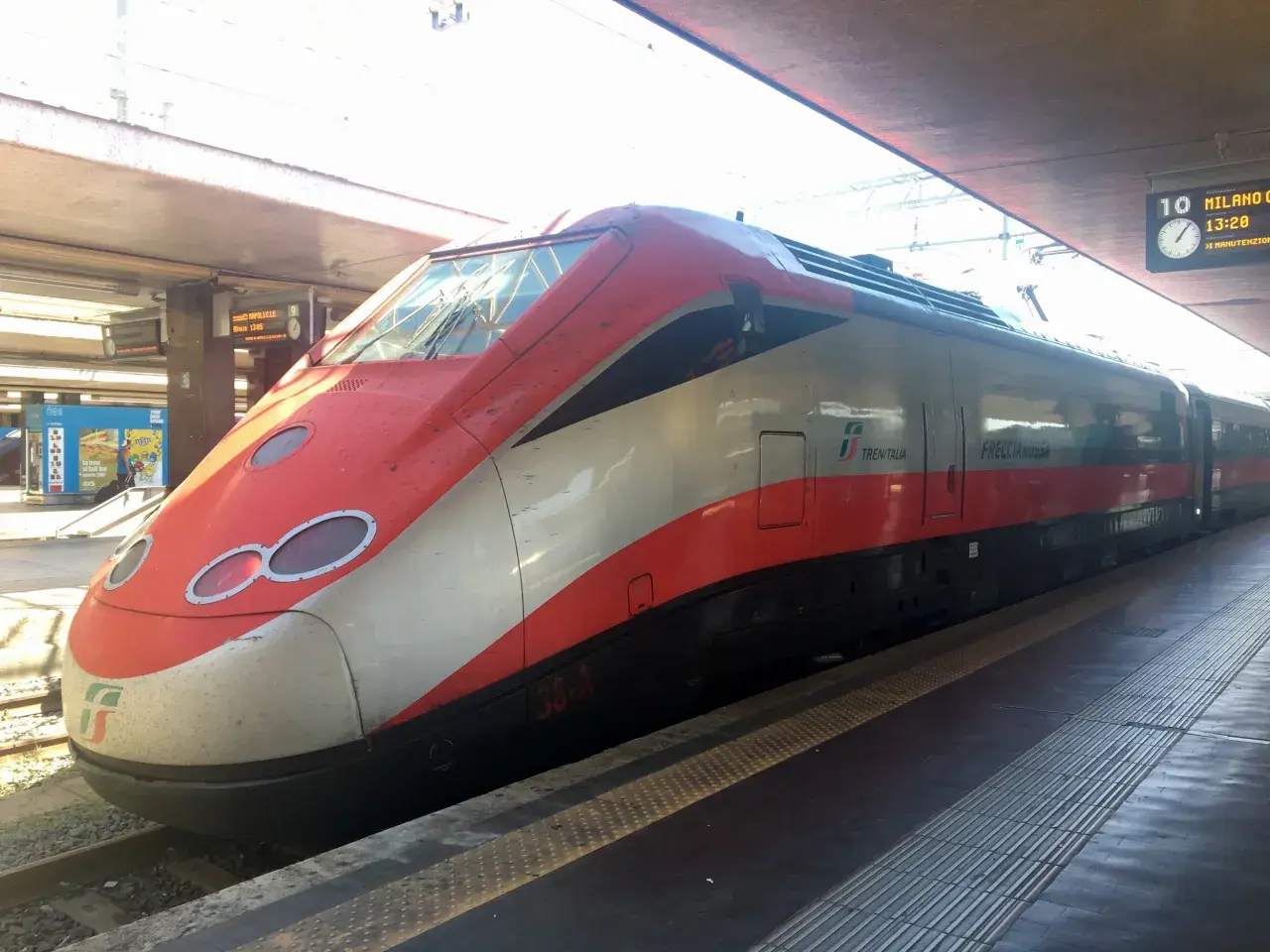 Röda och vita höghastighetståget Frecciarossa står vid perrongen, redo för resan. Snart bär det av med tåg till Florens.