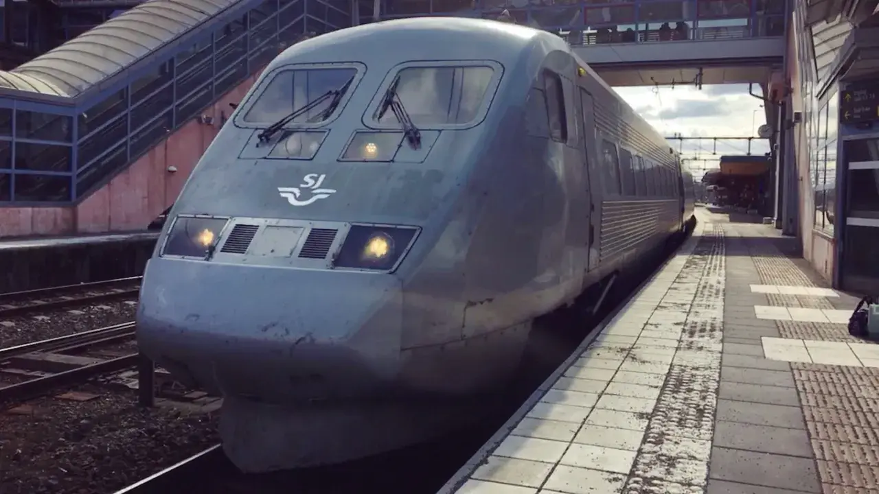 Grått SJ-tåg står vid perrongen, redo för en interrail-resa genom Sverige.