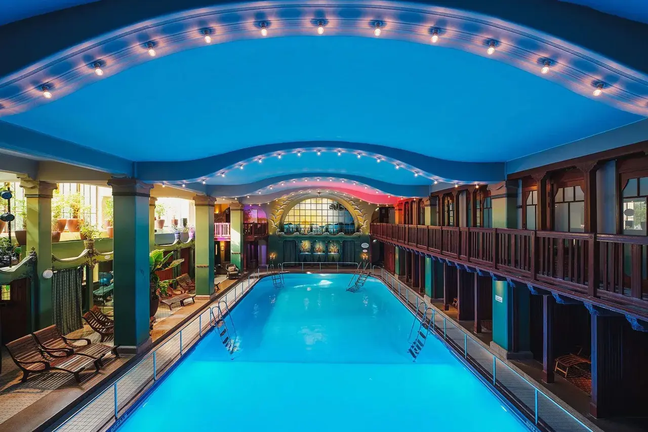 Ett vackert spa hotell i Stockholm med en stor inomhuspool, omgiven av grönska och trädetaljer.