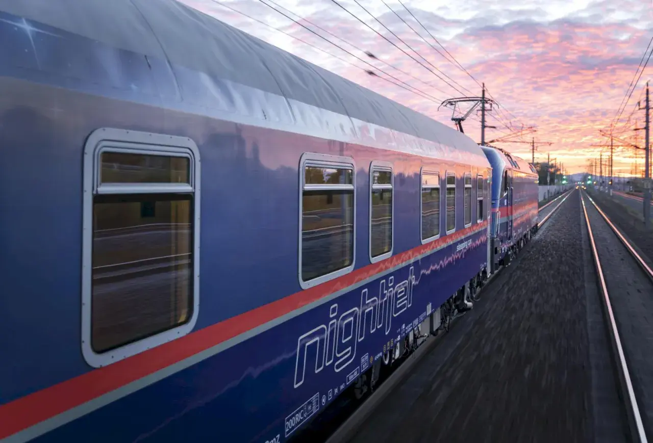 Nattåg köpenhamn paris, Nightjet-tåget susar fram genom ett vackert kvällslandskap med rosa moln.