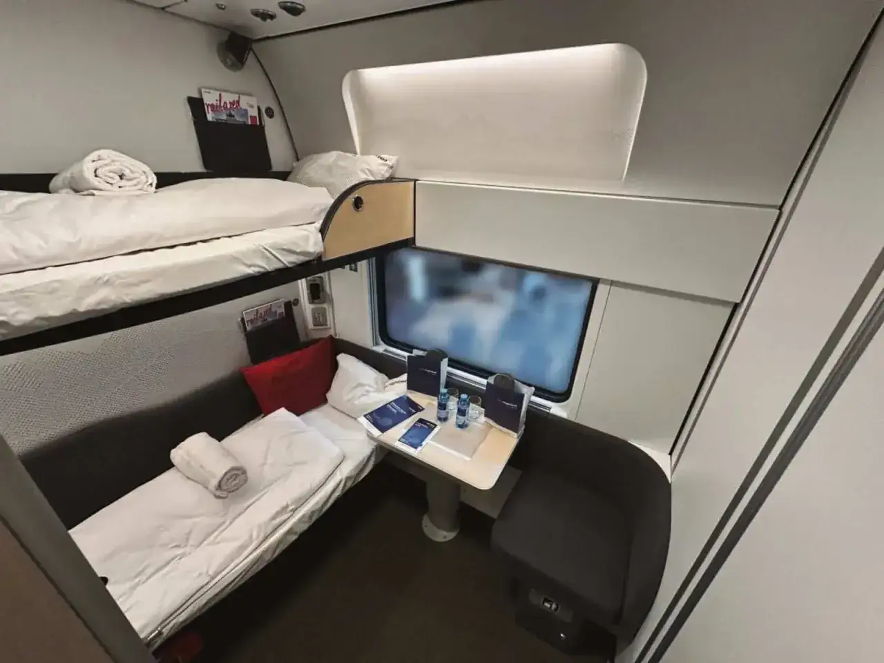 Sovhytt i ett nattåg till München, med våningssängar, bord och sittplats.
