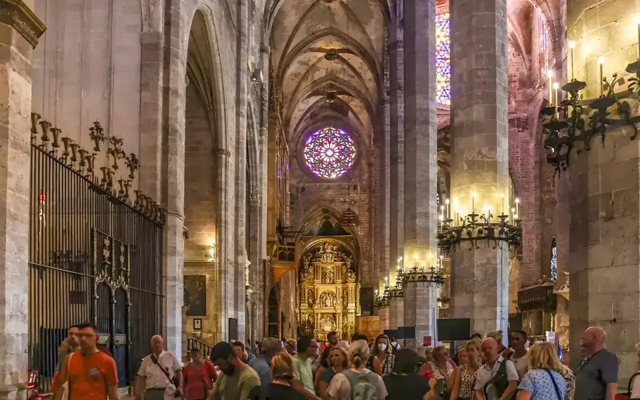 Besökare beundrar katedralens interiör i Palma de Mallorca, med dess imponerande rosettfönster och gyllene altare.