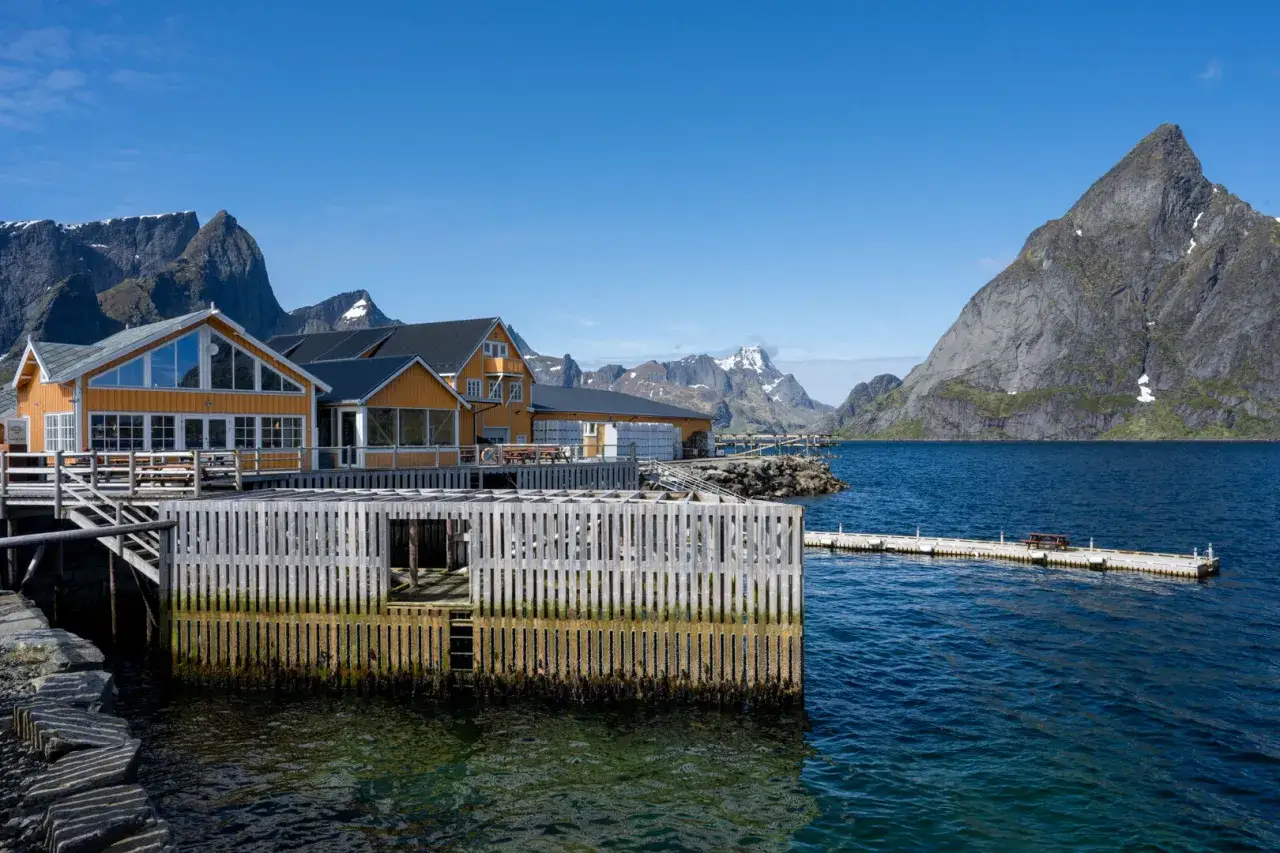 Gula hus vid vattnet med berg i bakgrunden. En perfekt vy för en Lofoten resa.