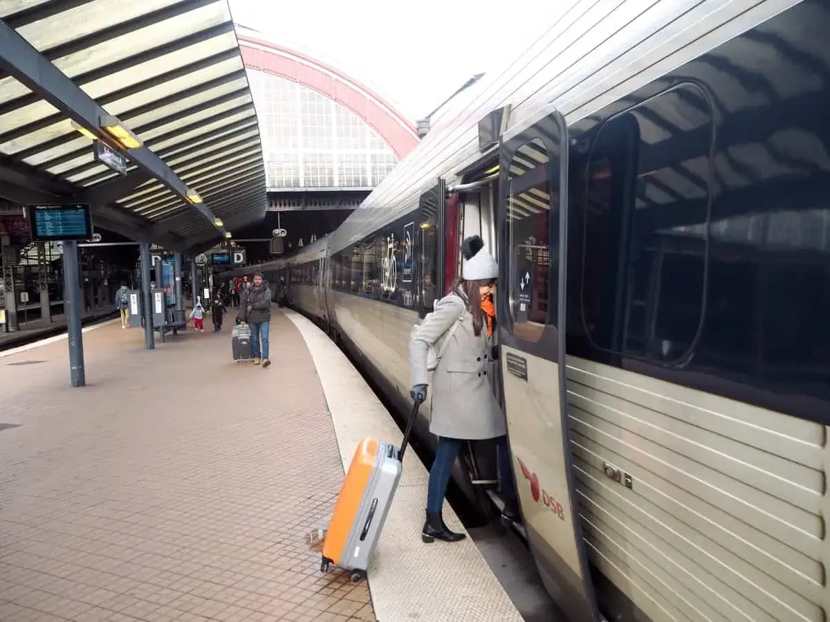 Resa med tåg Köpenhamn Hamburg med DSB. En kvinna med resväska stiger på ett tåg.
