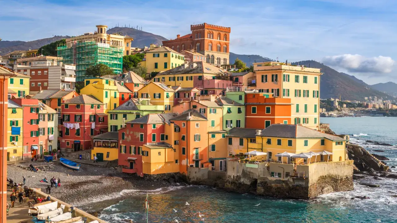 Färgstarka hus klättrar uppför kullen i Camogli, Italien, med havet som sköljer mot klipporna nedanför.