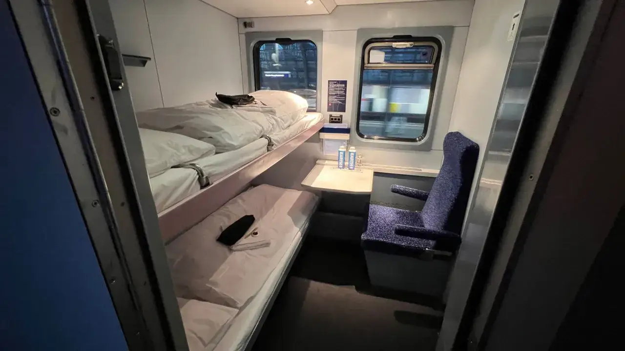 Sovkup&eacute; p&aring; ett natt&aring;g, redo f&ouml;r resan med natt&aring;g K&ouml;penhamn Paris. Tv&aring; b&auml;ddar, en stol och f&ouml;nster med utsikt.