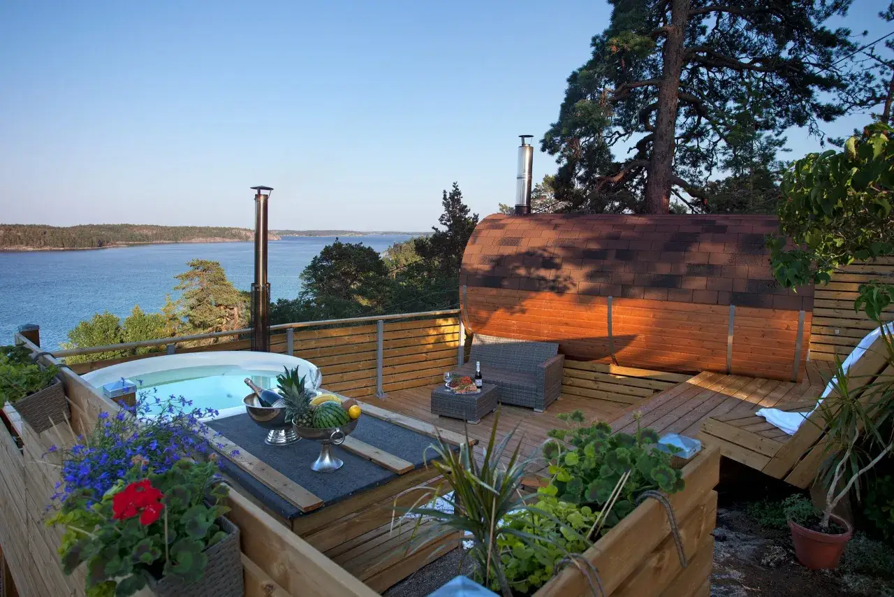 Avkopplande utomhusjacuzzi och bastu med utsikt över vattnet, perfekt för ett spa hotell i Stockholm.