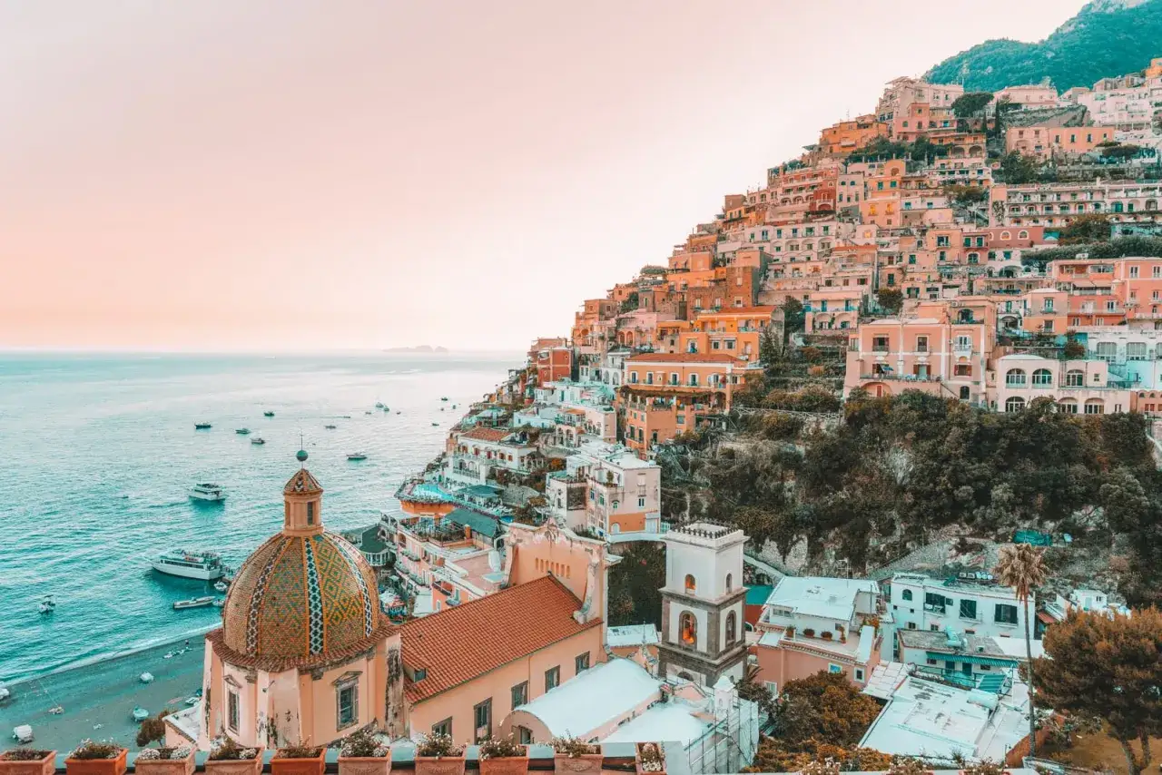 Färgstarka hus klättrar uppför en brant sluttning vid havet, en vy som utstrålar mysiga resmål i Italien.