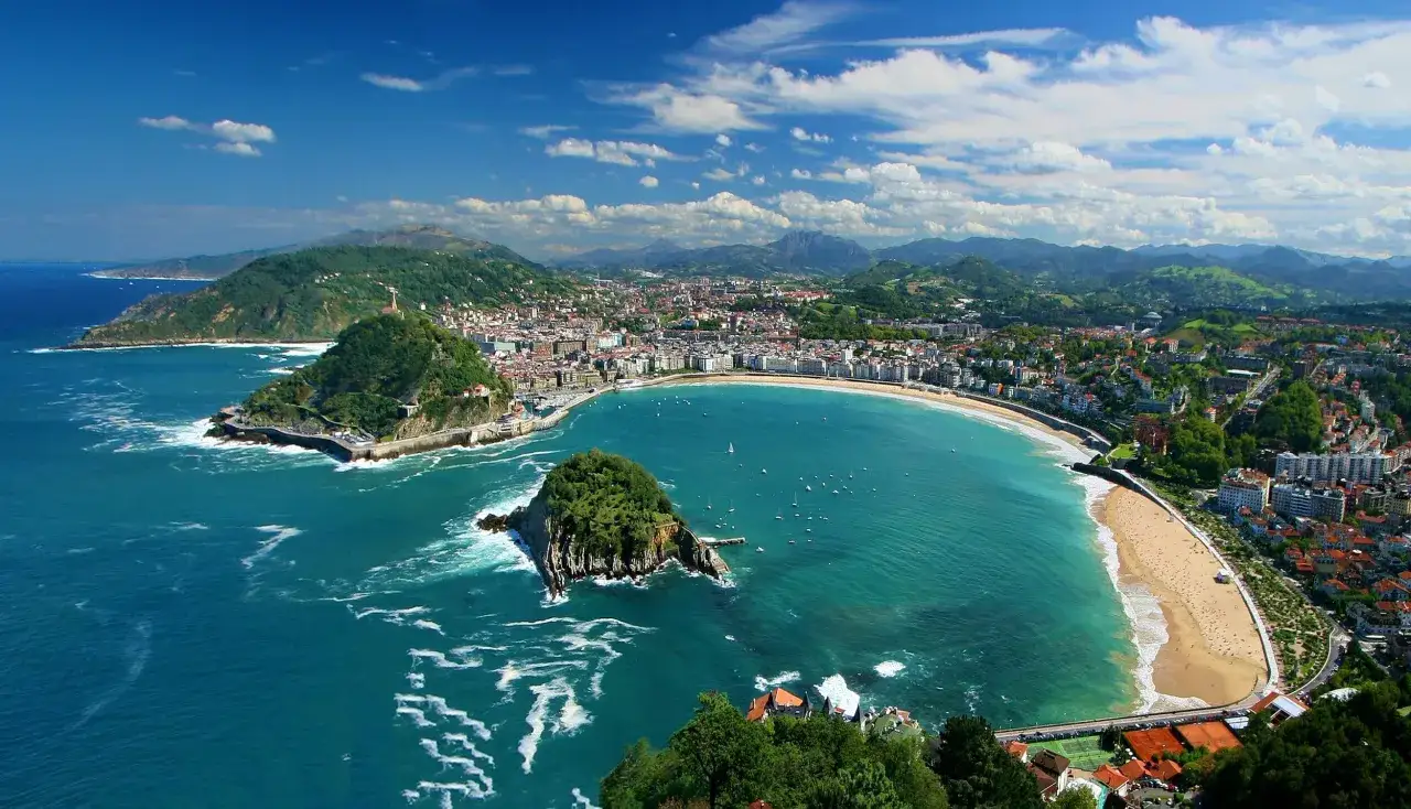 Vacker vy över San Sebastián, en pärla i Baskien, Spanien. En bukt med turkost vatten, en gyllene strand och gröna kullar som omger staden.