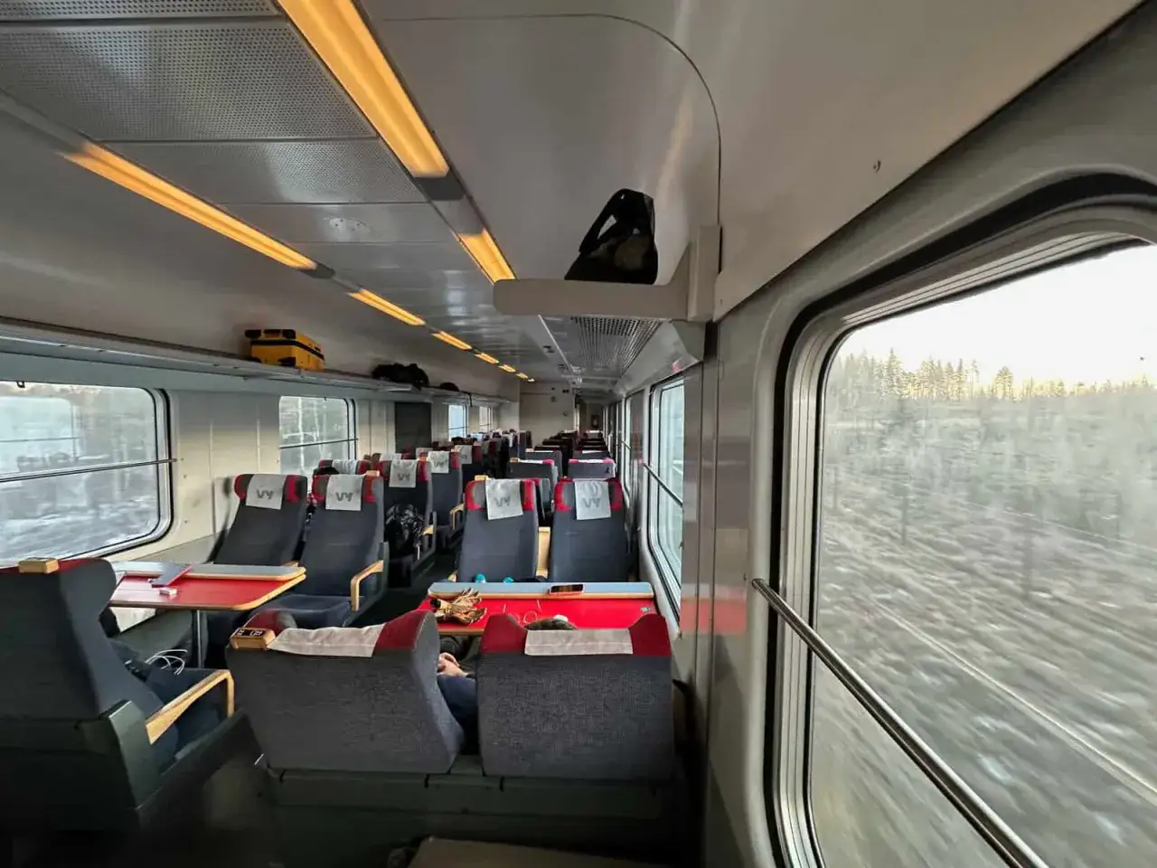 Tåg till Luleå från Stockholm. Tomma säten i tågvagnen med utsikt över snöig skog.