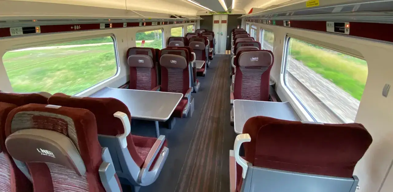 Tomma s&auml;ten i ett t&aring;g, troligen p&aring; v&auml;g till London. F&ouml;nstren visar gr&ouml;na f&auml;lt som svischar f&ouml;rbi.