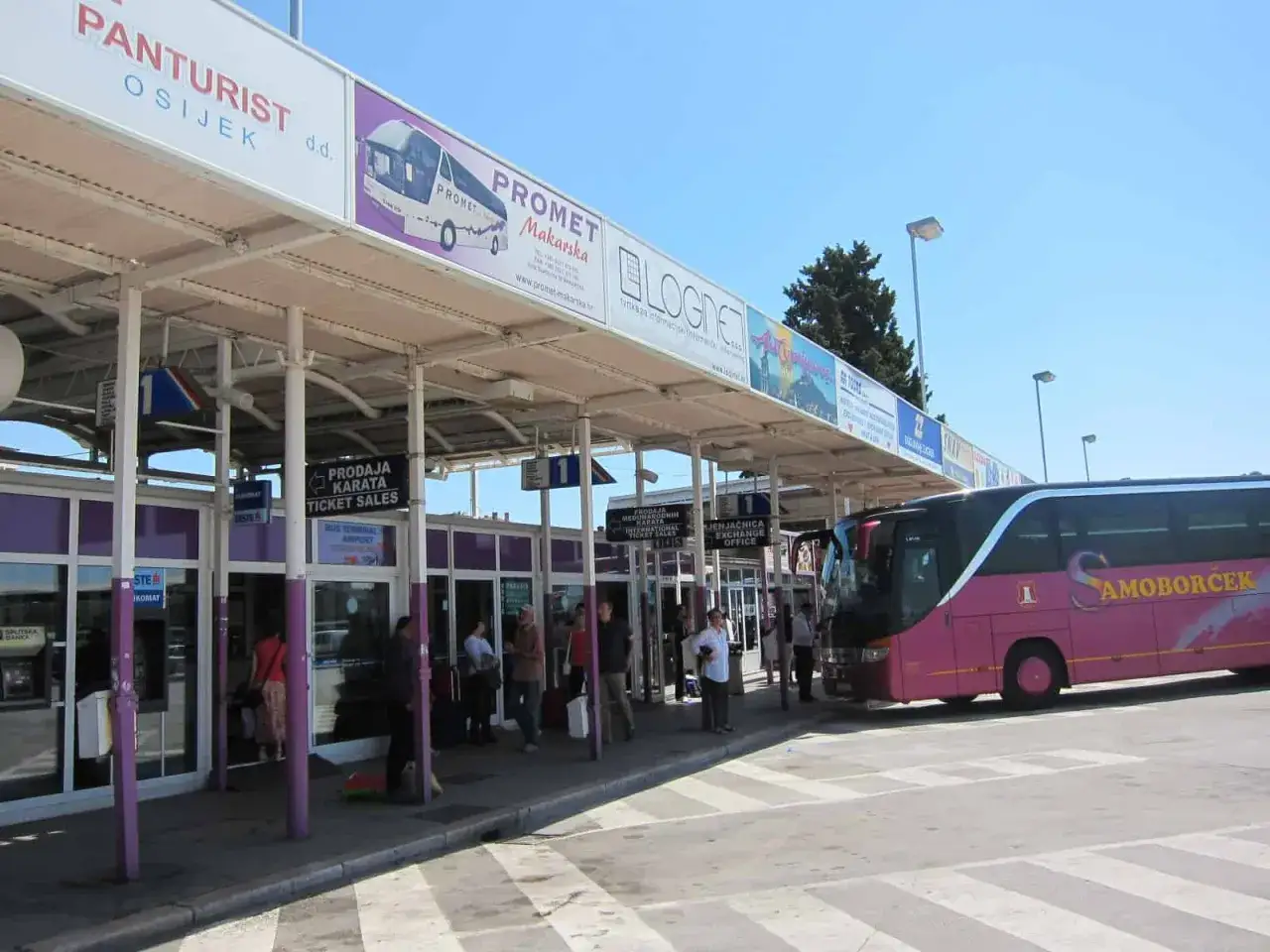 Rosa buss vid busstationen i Kroatien. Biljetf&ouml;rs&auml;ljning och v&auml;xlingskontor syns.