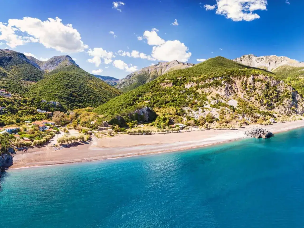 En vacker strand med turkost vatten och gröna berg i bakgrunden på Evia, Grekland.