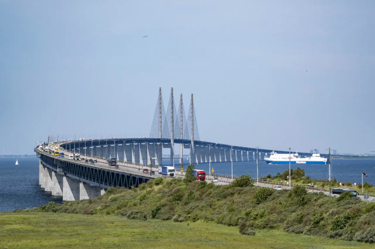 Öresundsbron, bron till Danmark, med bilar och en färja i Öresund.